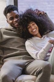 Beloved African American couple cuddling and smiling on couch